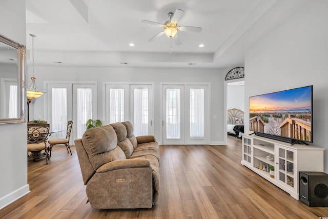 living room featuring wood finished floors, baseboards, recessed lighting, ceiling fan, and a raised ceiling