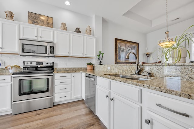 kitchen featuring visible vents, a sink, white cabinetry, light wood-style floors, and appliances with stainless steel finishes