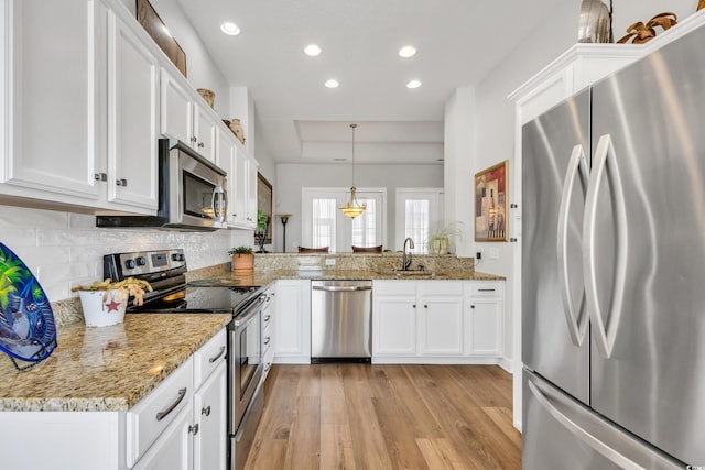 kitchen with white cabinets, stainless steel appliances, light wood-type flooring, and a sink