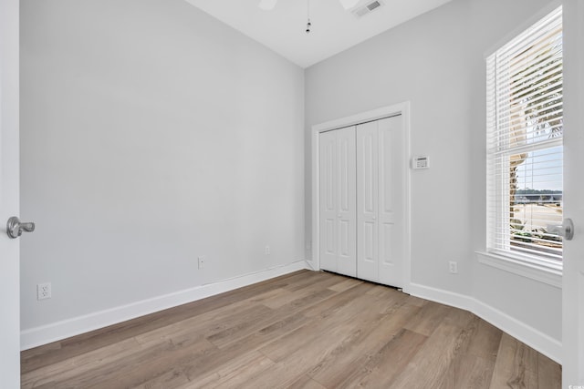 unfurnished bedroom with baseboards, visible vents, light wood finished floors, ceiling fan, and a closet