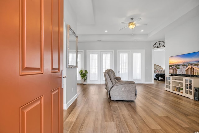 foyer entrance featuring light wood finished floors, baseboards, recessed lighting, a raised ceiling, and a ceiling fan