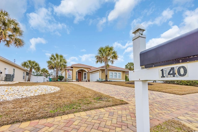 view of front of property with stucco siding, decorative driveway, fence, cooling unit, and an attached garage