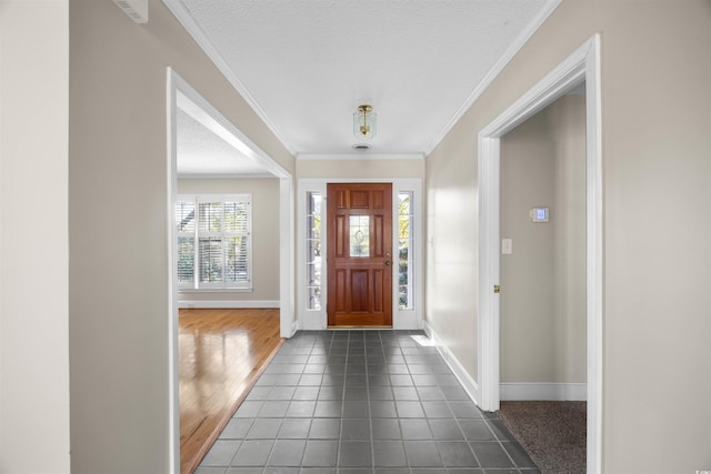 foyer featuring a textured ceiling, ornamental molding, and baseboards