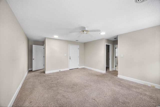 empty room with a textured ceiling, carpet flooring, and baseboards