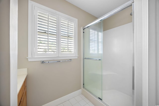 full bath featuring tile patterned flooring, a shower stall, vanity, and baseboards