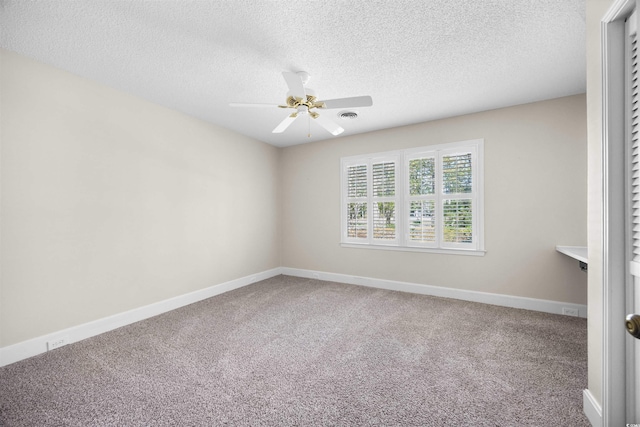 carpeted spare room featuring a ceiling fan, visible vents, a textured ceiling, and baseboards