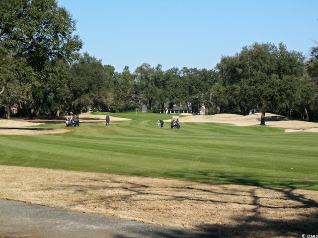 view of property's community with view of golf course and a yard