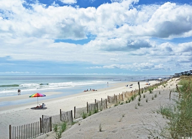 view of water feature with fence and a beach view