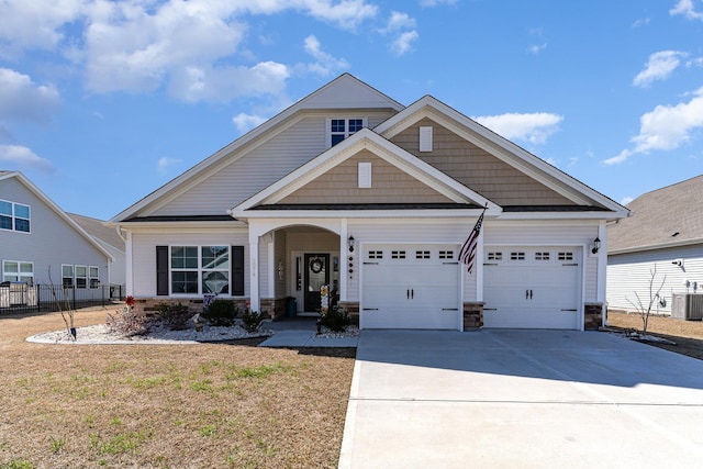 craftsman inspired home with an attached garage, stone siding, fence, and concrete driveway