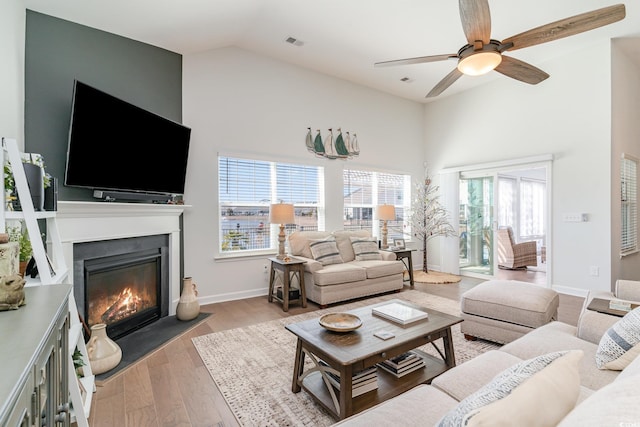 living room featuring a fireplace with flush hearth, visible vents, plenty of natural light, and light wood finished floors