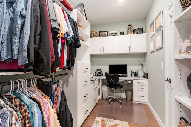 office space with built in desk, baseboards, and wood finished floors