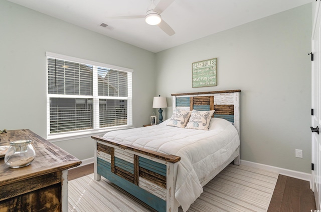 bedroom with visible vents, baseboards, and wood finished floors