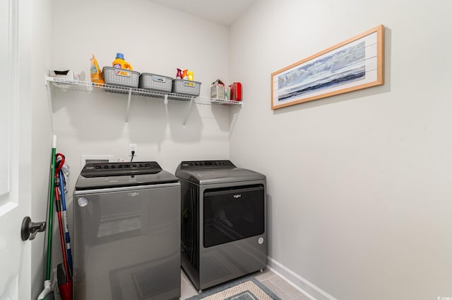 laundry area with baseboards, laundry area, light tile patterned floors, and washer and dryer