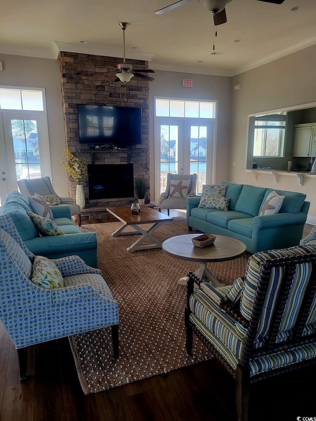 living room featuring ceiling fan, ornamental molding, a fireplace, and wood finished floors