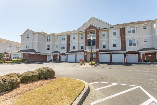 multi unit property featuring an attached garage, driveway, a residential view, and brick siding