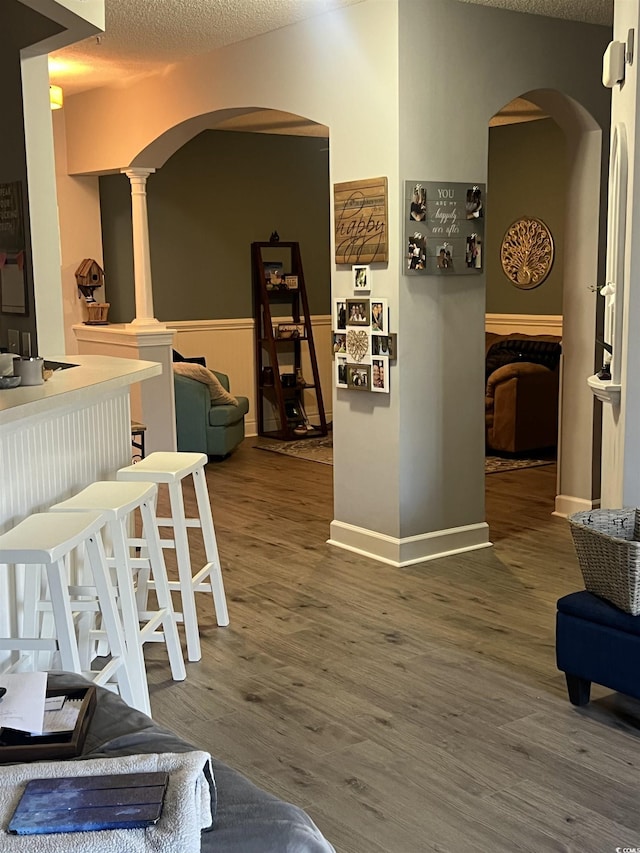 interior space featuring arched walkways, a textured ceiling, and wood finished floors