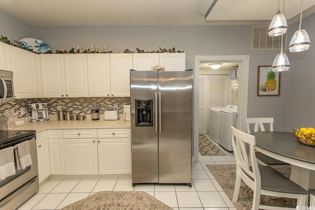 kitchen featuring white cabinets, stainless steel appliances, visible vents, and washer and dryer