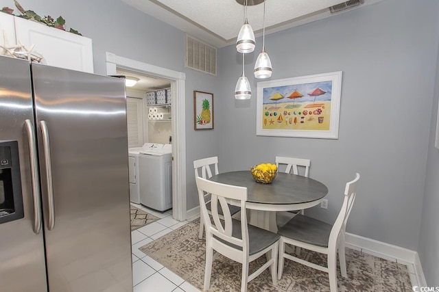 dining space with light tile patterned floors, baseboards, visible vents, and separate washer and dryer