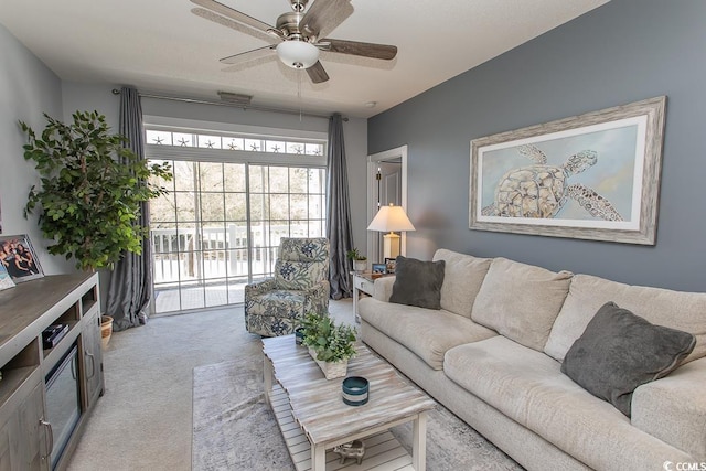 living area featuring light carpet and ceiling fan