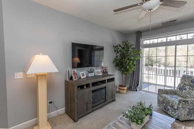 living room featuring light carpet, ceiling fan, visible vents, and a textured ceiling