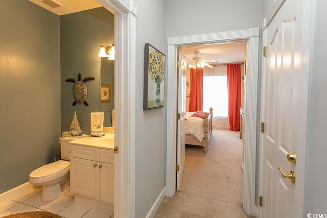 corridor with light carpet, light tile patterned floors, visible vents, and baseboards