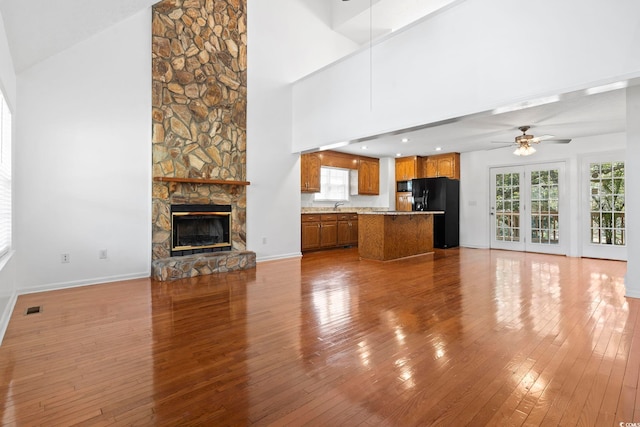 unfurnished living room featuring ceiling fan, a fireplace, wood finished floors, and baseboards