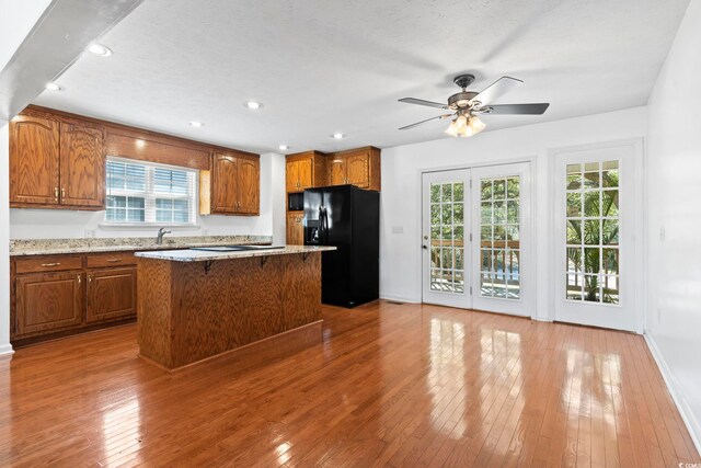 3615 Sunfish St, Murrells Inlet, SC 29576 - kitchen with ceiling fan, brown cabinets, black fridge, and hardwood / wood-style floors
