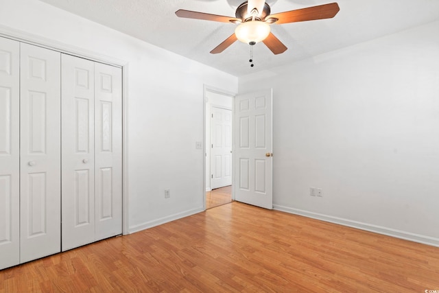 unfurnished bedroom with light wood-style floors, a closet, ceiling fan, and baseboards