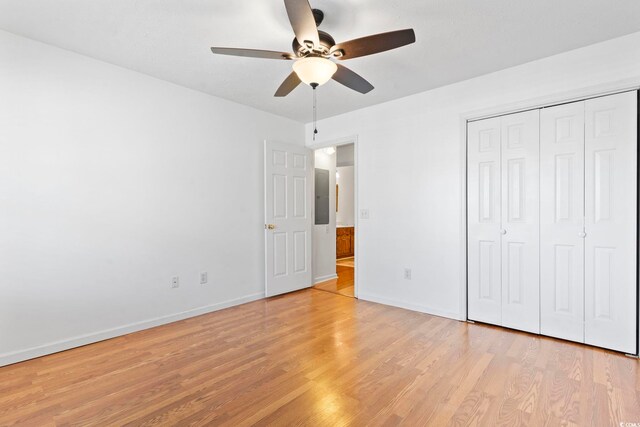 unfurnished bedroom with a closet, ceiling fan, light wood-style flooring, and baseboards