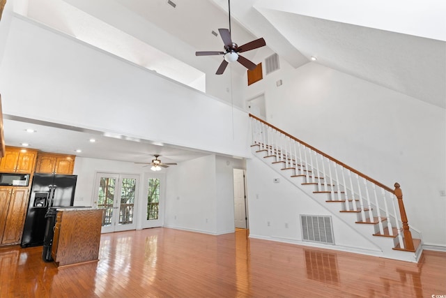 unfurnished living room featuring stairs, french doors, light wood-type flooring, and visible vents