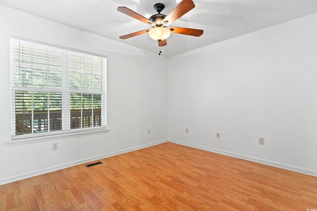 empty room with ceiling fan, light wood-type flooring, visible vents, and baseboards