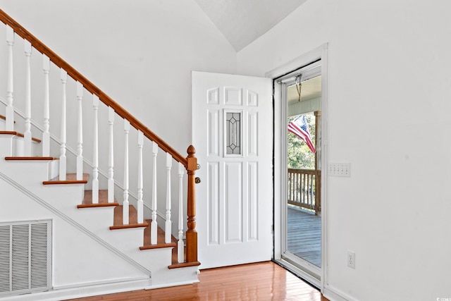 entrance foyer featuring lofted ceiling, light wood-style flooring, stairs, and visible vents