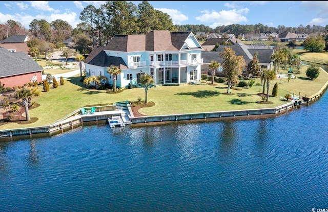 back of property with a lawn, a water view, a residential view, and a balcony