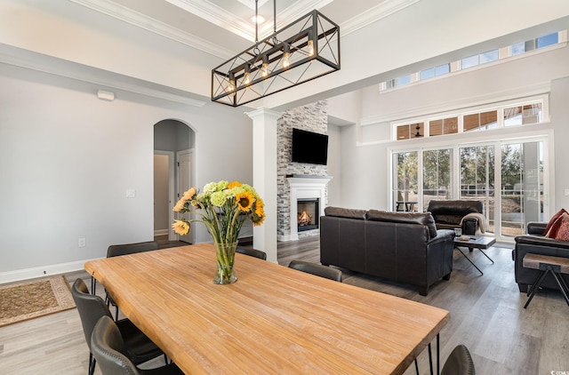 dining area featuring a large fireplace, a high ceiling, crown molding, and wood finished floors