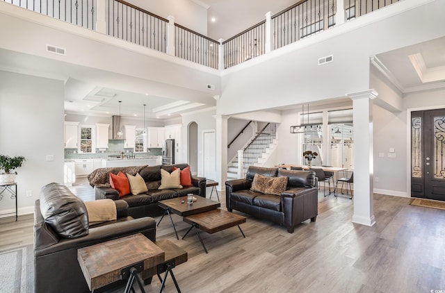 living room with ornamental molding, arched walkways, a raised ceiling, and visible vents