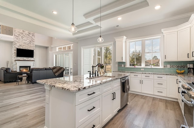 kitchen with stainless steel appliances, white cabinets, a sink, and decorative light fixtures