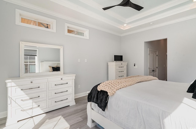 bedroom with ceiling fan, baseboards, light wood-type flooring, a raised ceiling, and crown molding