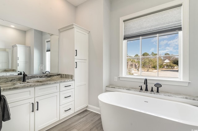 full bathroom with a freestanding bath, wood finished floors, vanity, and baseboards