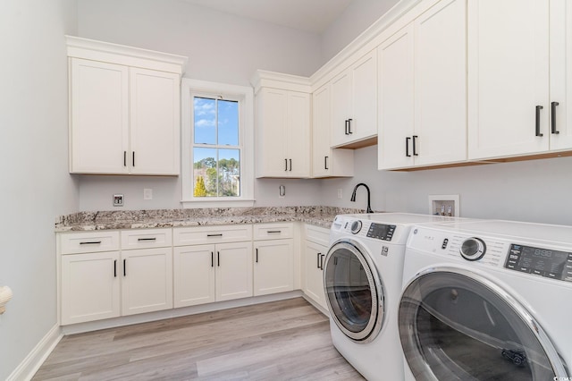 laundry area with cabinet space, baseboards, washer and dryer, light wood-style floors, and a sink