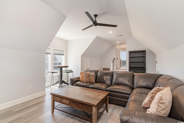 living room featuring visible vents, light wood-style flooring, vaulted ceiling, ceiling fan, and baseboards