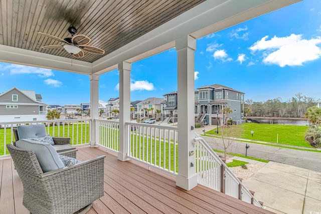 wooden terrace with ceiling fan, a residential view, a yard, and a water view