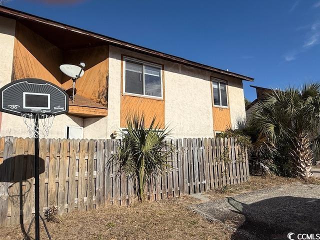 view of side of home with fence and stucco siding