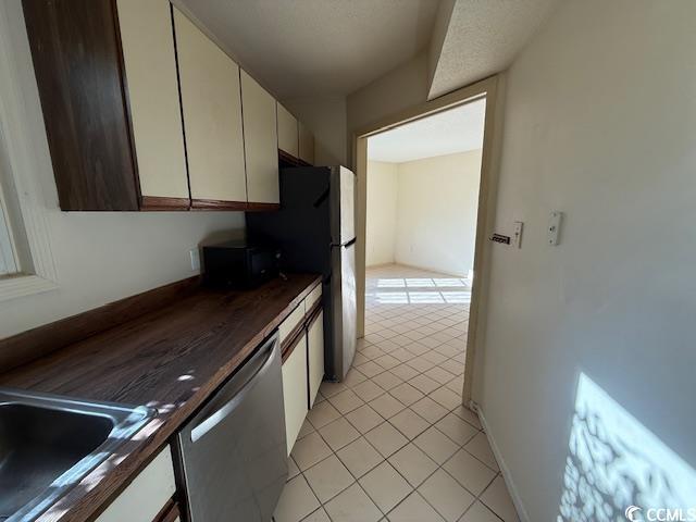 kitchen featuring light tile patterned floors, stainless steel dishwasher, white cabinetry, black microwave, and a sink