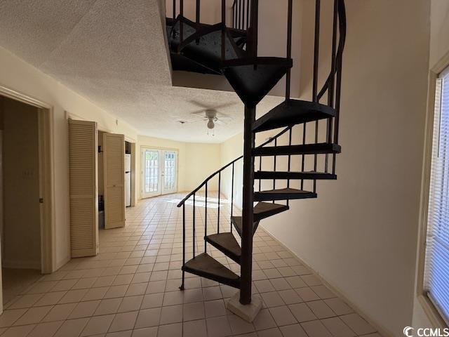 staircase with a textured ceiling, french doors, and tile patterned floors