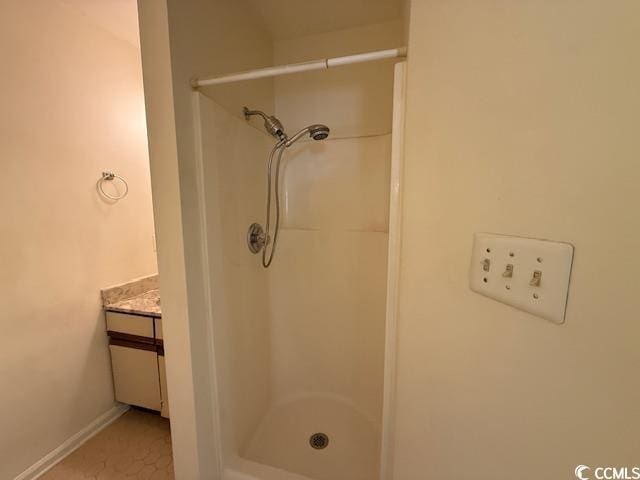 full bath with a stall shower, baseboards, and vanity