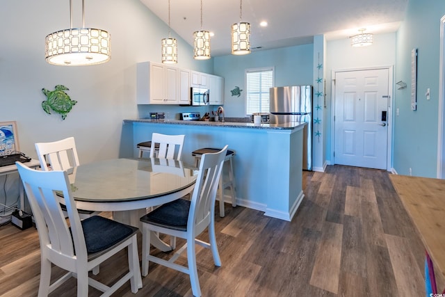 dining space featuring vaulted ceiling, baseboards, and dark wood finished floors