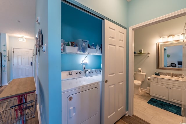 washroom with laundry area, washing machine and dryer, baseboards, and a sink