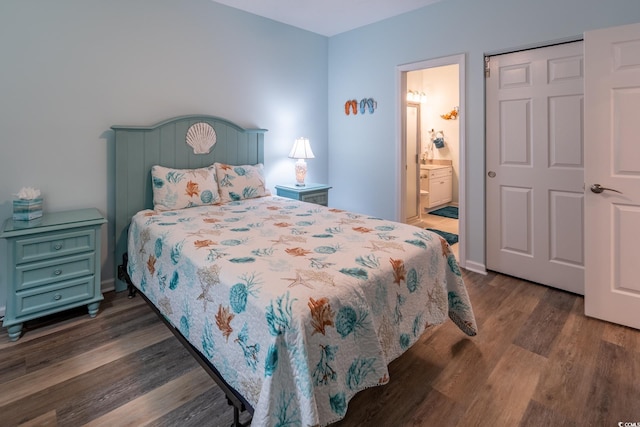 bedroom with dark wood-style floors, connected bathroom, and baseboards