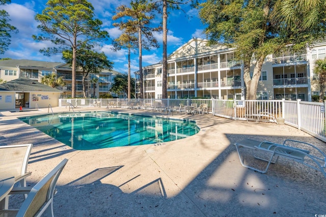 community pool with a patio area and fence