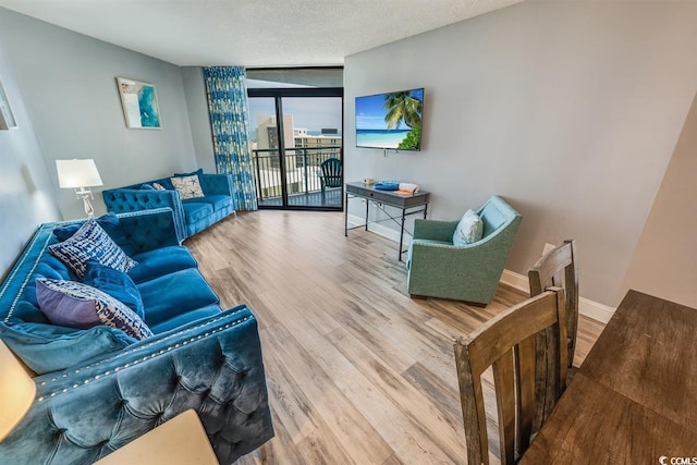 living room featuring floor to ceiling windows, a textured ceiling, baseboards, and wood finished floors